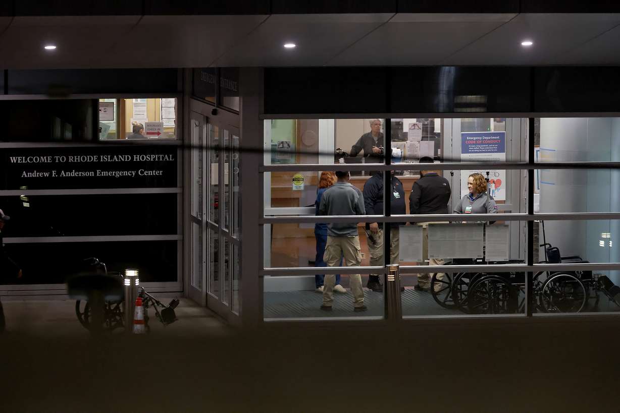 People stand at an entrance to Rhode Island Hospital in Providence, R.I., on Saturday, where victims from a shooting at Brown University were transported. Six of the victims were in critical, but stable condition.