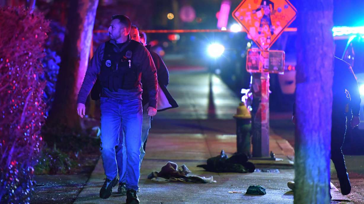A law enforcement official walks past articles of clothing on a sidewalk near an entrance to Brown University, Saturday, in Providence, R.I., during the investigation of a shooting.