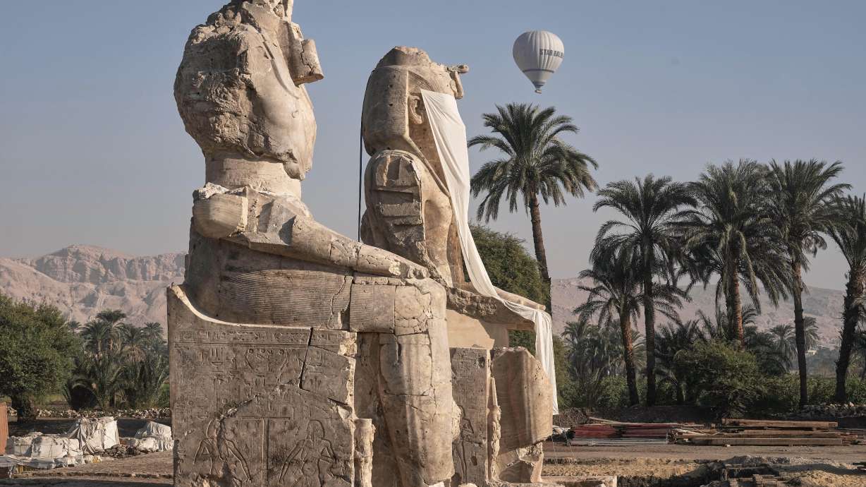 A hot air ballon flys over the assembly of two giant alabaster statues for Pharoah Amenhotep III, before the official opening, in the southern city of Luxor, Egypt, Sunday.