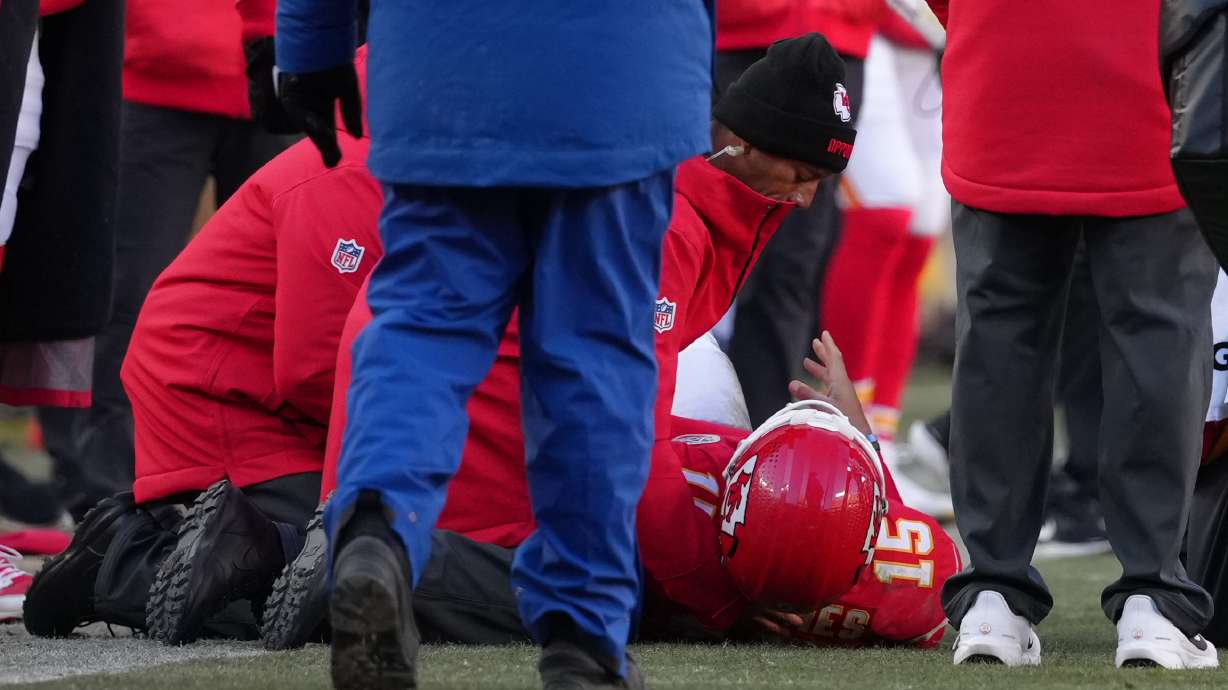 Kansas City Chiefs quarterback Patrick Mahomes (15) is checked on after being injured during the second half of an NFL football game against the Los Angeles Chargers Sunday, Dec. 14, 2025, in Kansas City, Mo.