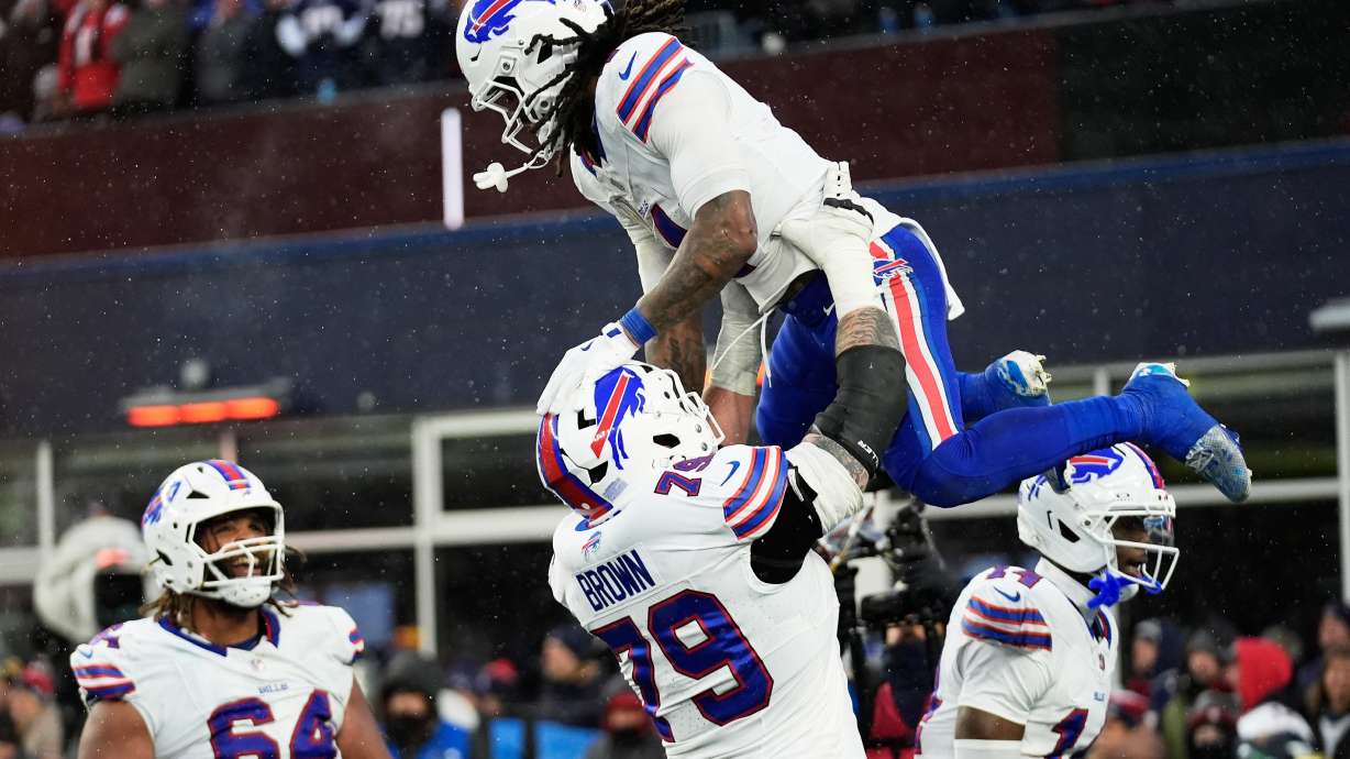 Buffalo Bills running back James Cook III, top, celebrates with offensive tackle Spencer Brown (79) after scoring against the New England Patriots during the second half of an NFL football game in Foxborough, Mass., Sunday, Dec. 14, 2025.