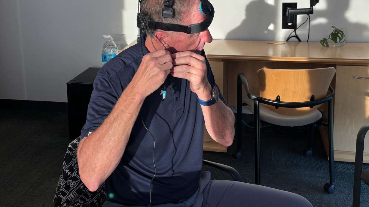 Former BYU football player Jim Herrmann tries on a light therapy headset at the University of Utah neuroscience building. Herrmann has agreed to participate in a study on infrared light therapy called photobiomodulation and publicize his results.