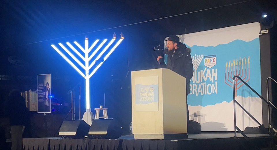Rabbi Chaim Zippel speaks before a crowd during the Hanukkah celebration at Electric Park in Lehi on Monday.