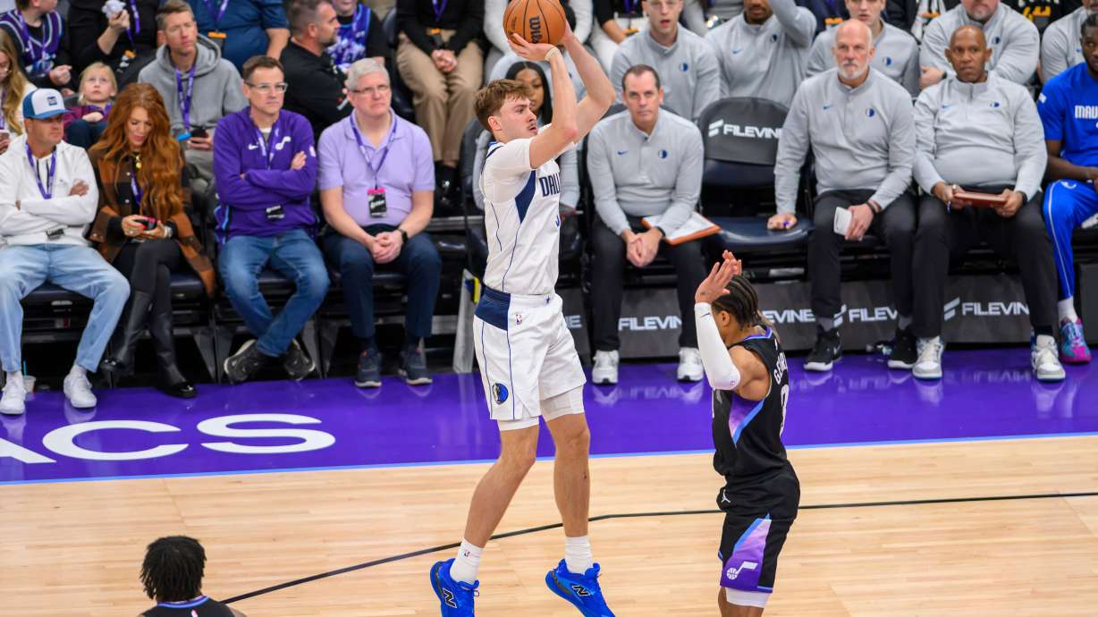 Dallas Mavericks forward Cooper Flagg, center, shoots over Utah Jazz guard Keyonte George, right, during the first half of an NBA basketball game, Monday, Dec. 15, 2025, in Salt Lake City.