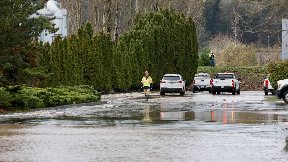 A response team crew member walks by standing water from a levee breach on the Green River in Tukwila, Wash., Monday. Gov. Bob Ferguson said Tuesday the damages like these from recent rain and flooding are profound, but more is on the way.