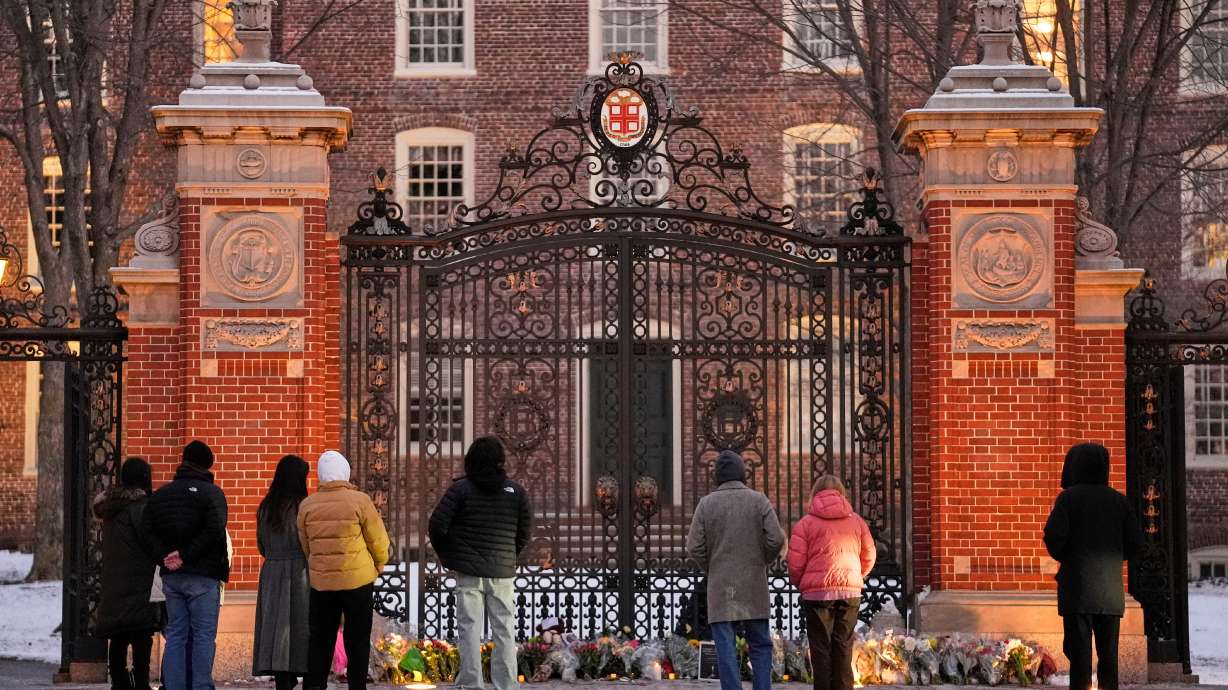 Visitors pause at a makeshift memorial for the victims of Saturday's shooting, at the Van Wickle Gate at Brown University, Monday, in Providence, R.I.