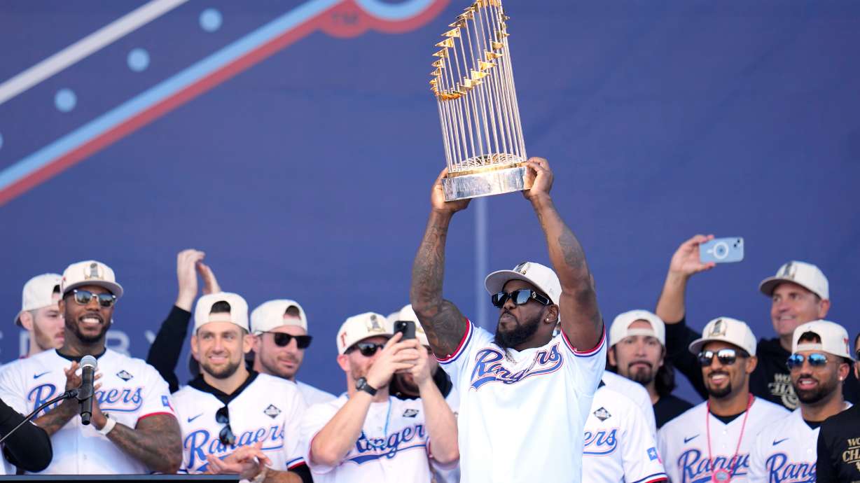 FILE - Texas Rangers' Adolis Garcia, surrounded by teammates and staff, holds up the Commissioner's Trophy during a World Series baseball championship celebration, Friday, Nov. 3, 2023, in Arlington, Texas.