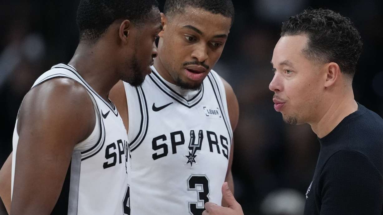 San Antonio Spurs head coach Mitch Johnson, right, talks with San Antonio Spurs guard De'Aaron Fox (4) and forward Keldon Johnson (3) during the second half of an NBA basketball game against the Sacramento Kings in San Antonio, Sunday, Nov. 16, 2025.
