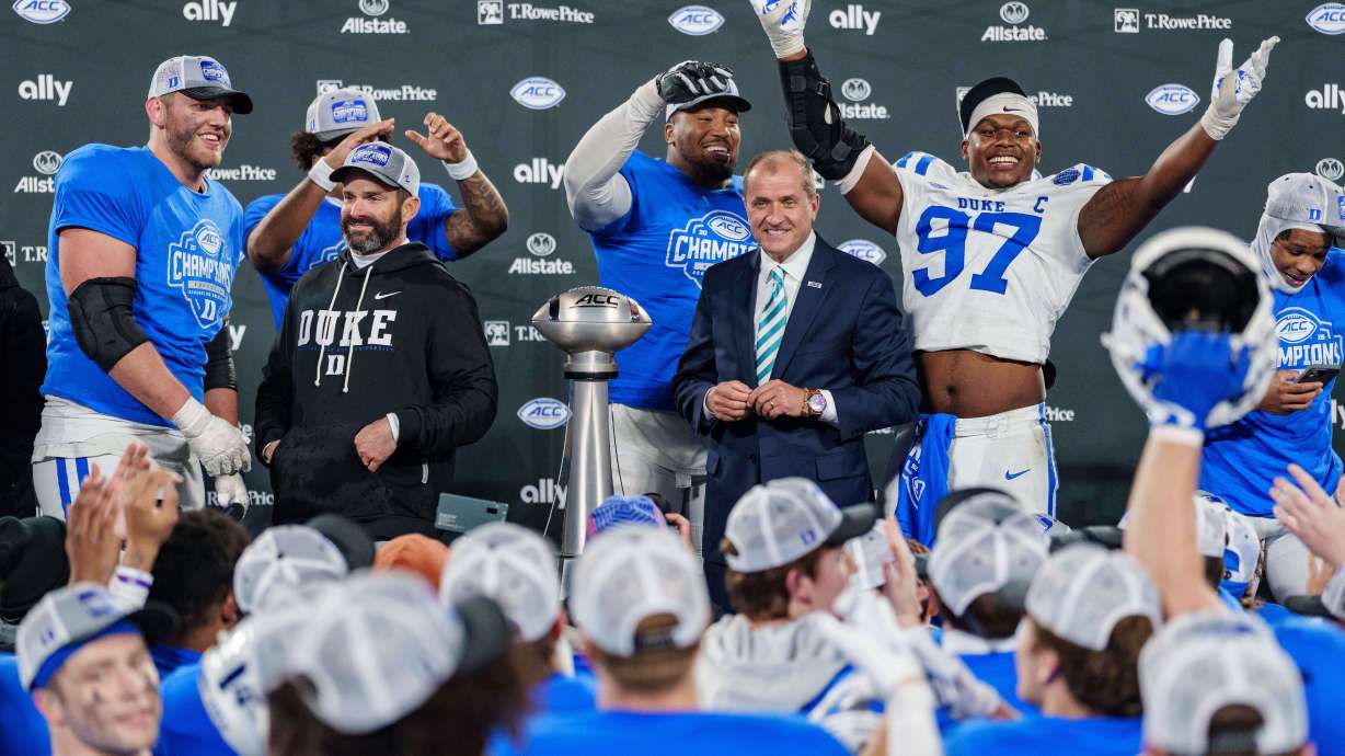 Duke players celebrate with the trophy after defeating Virginia in the Atlantic Coast Conference championship NCAA college football game Saturday, Dec. 6, 2025, in Charlotte, N.C.