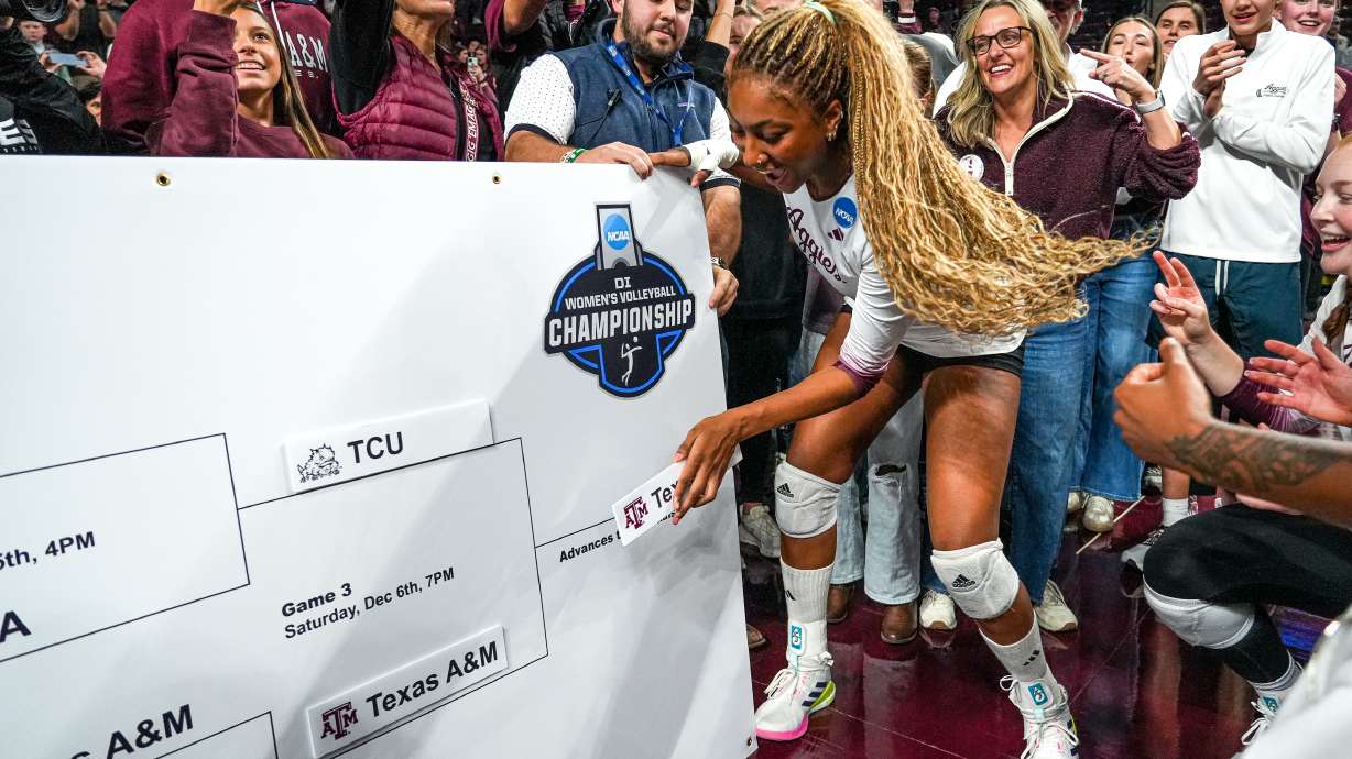FILE - Texas A&M middle blocker Morgan Perkins, center, places the Texas A&M logo on an NCAA bracket after winning the NCAA Division I volleyball playoff game against TCU, Dec. 6, 2025, in College Station, Texas.