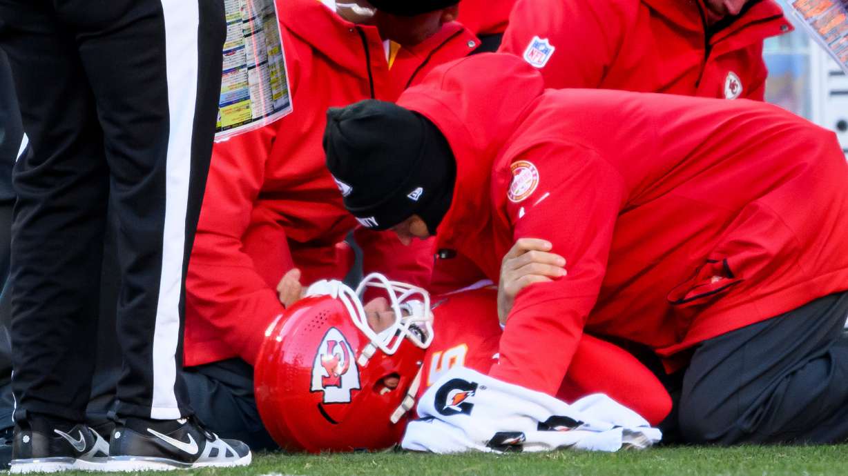 FILE - Rick Burkholder, Chiefs Vice President of Sports Medicine and Performance, talks to Chiefs quarterback Patrick Mahomes, on ground, after Mahomes was injured during the second half of an NFL football game against the Los Angeles Chargers, Sunday, Dec. 14, 2025 in Kansas City, Mo.