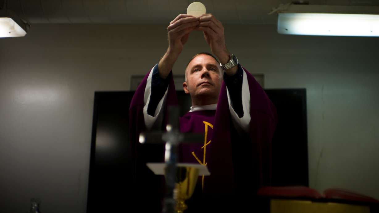 Navy Chaplain Lt. Cmdr. Ben Garrett performs the sacrament of the Eucharist in the chapel of the USS Bataan on March 15, 2023, at Norfolk Naval Station in Norfolk, Va. Before joining the U.S. Navy, Chaplain Garrett was a priest in Washington, D.C.