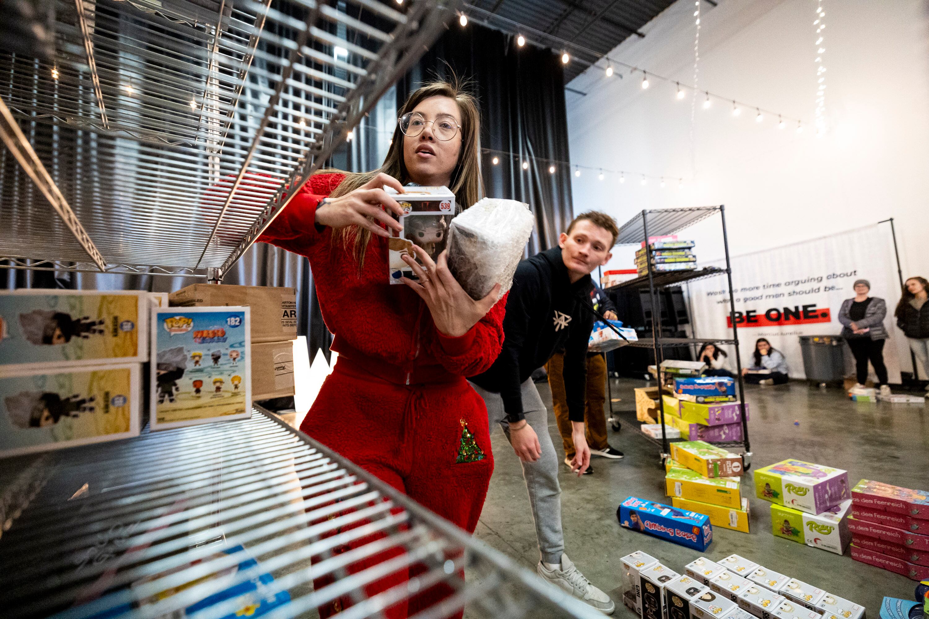 Volunteers Nichelle Livingston, center, and Hunter Rex take toys to lay out for community members to take during a toy drive at the headquarters of We Are The They in Lehi on Wednesday.