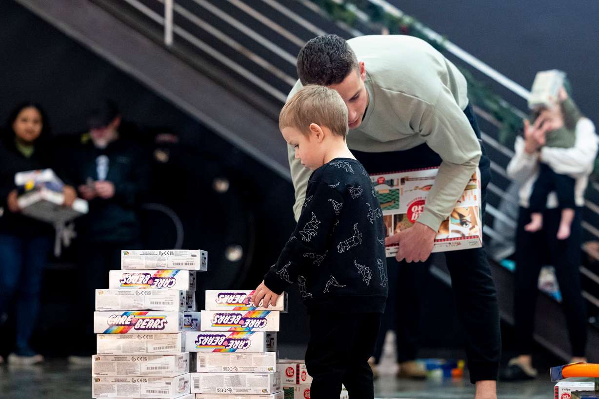 Caspian DeHart, 2, of American Fork, listens to his father, Tanner, as he browses toys during a toy drive at the headquarters of We Are The They in Lehi on Wednesday.