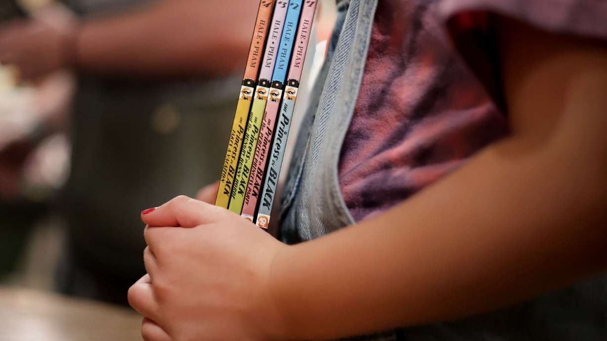 A girl holds copies of Shannon Hale’s books at Folklore Bookshop in Midway on Sept. 17. Hale is the bestselling, award-winning author of 50 books for all ages, selling more than 15 million copies and translated into 25 languages.