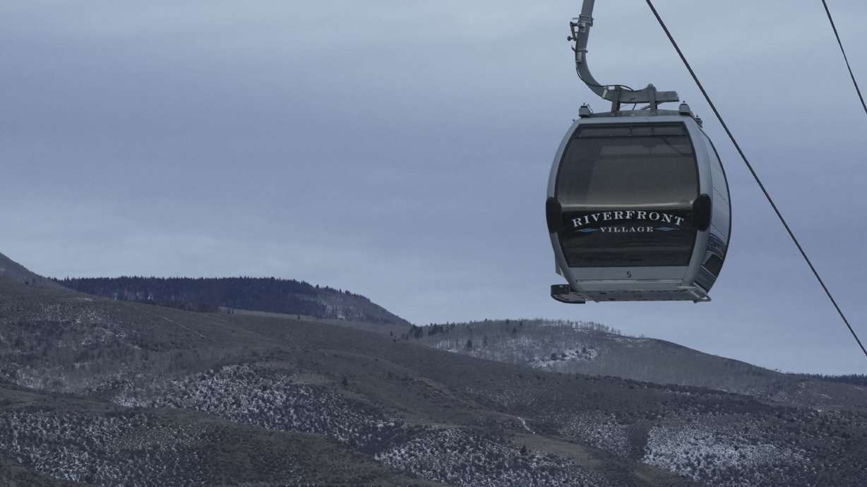 A gondola hangs in front of snow-scarce mountains Thursday, Dec. 18, 2025, in Avon, Colo.