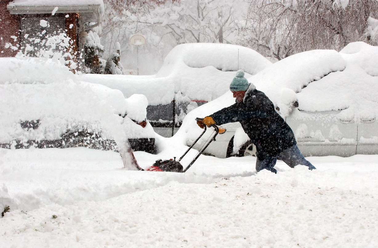 Tom Smith uses his snowblower to clear his neighbor's driveway on Evergreen Avenue in Salt Lake City during a snowstorm on Dec. 26, 2003.