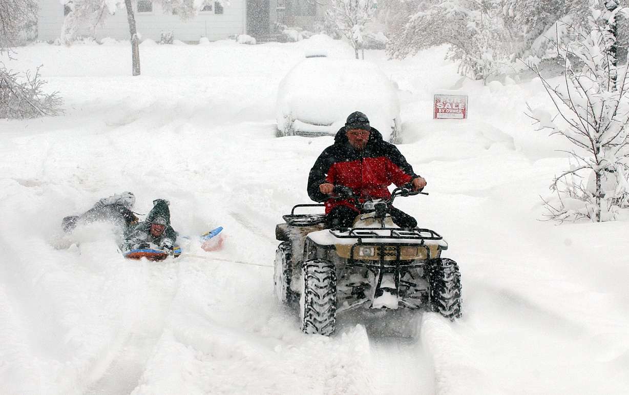 Jim Keech drives a four-wheeler pulling Robin Sumsion and Marin Keech on Claybourne Avenue in Salt Lake City during a snowstorm. Jim said this is the first time he has been able to do this since 1993.