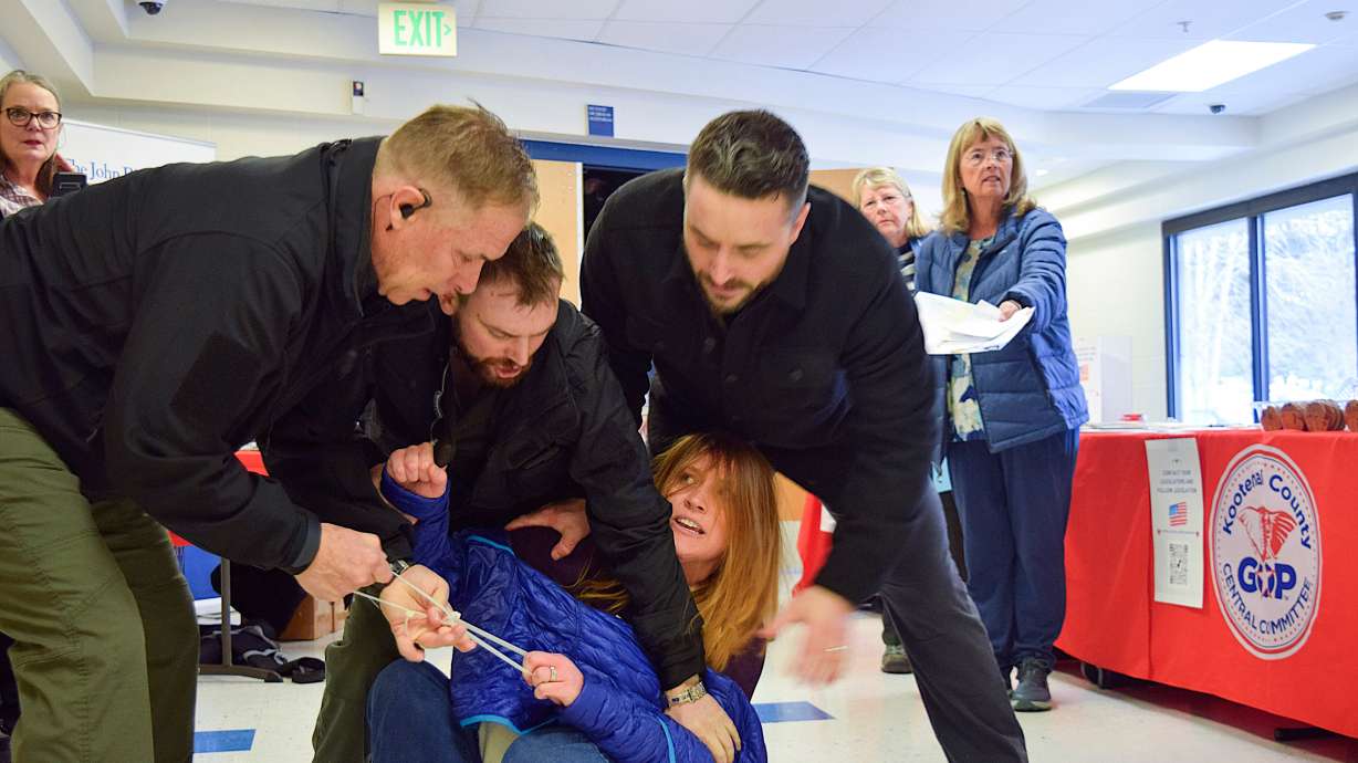 Employees of LEAR Asset Management drag Teresa Borrenpohl out of a town hall meeting on Feb. 22, in Post Falls, Idaho. The security company's owner was found guilty of misdemeanor battery and violating uniform rules in a split verdict Thursday.