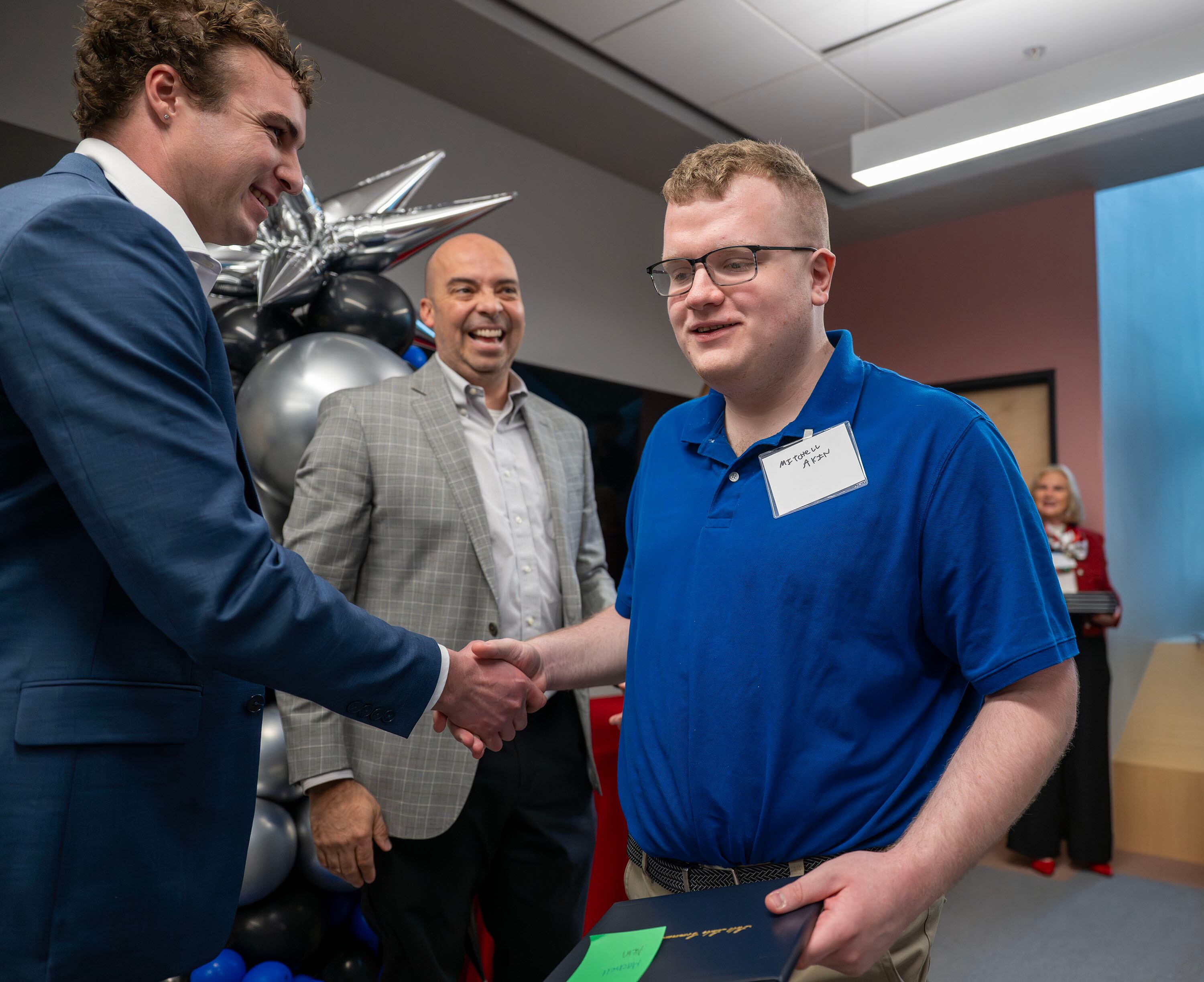 Mitchell Akin tries to walk away as he shakes hands with Zachary Ingrey, associate dean and director of advanced manufacturing at Salt Lake Community College, as Johnny Ferry of the Utah Manufacturers Association laughs during the inaugural graduation exercises of a SLCC-sponsored vocational training program for adults with autism at Nextwork Autism Program in South Salt Lake City, on Friday. Akin's mother was present at the ceremony.