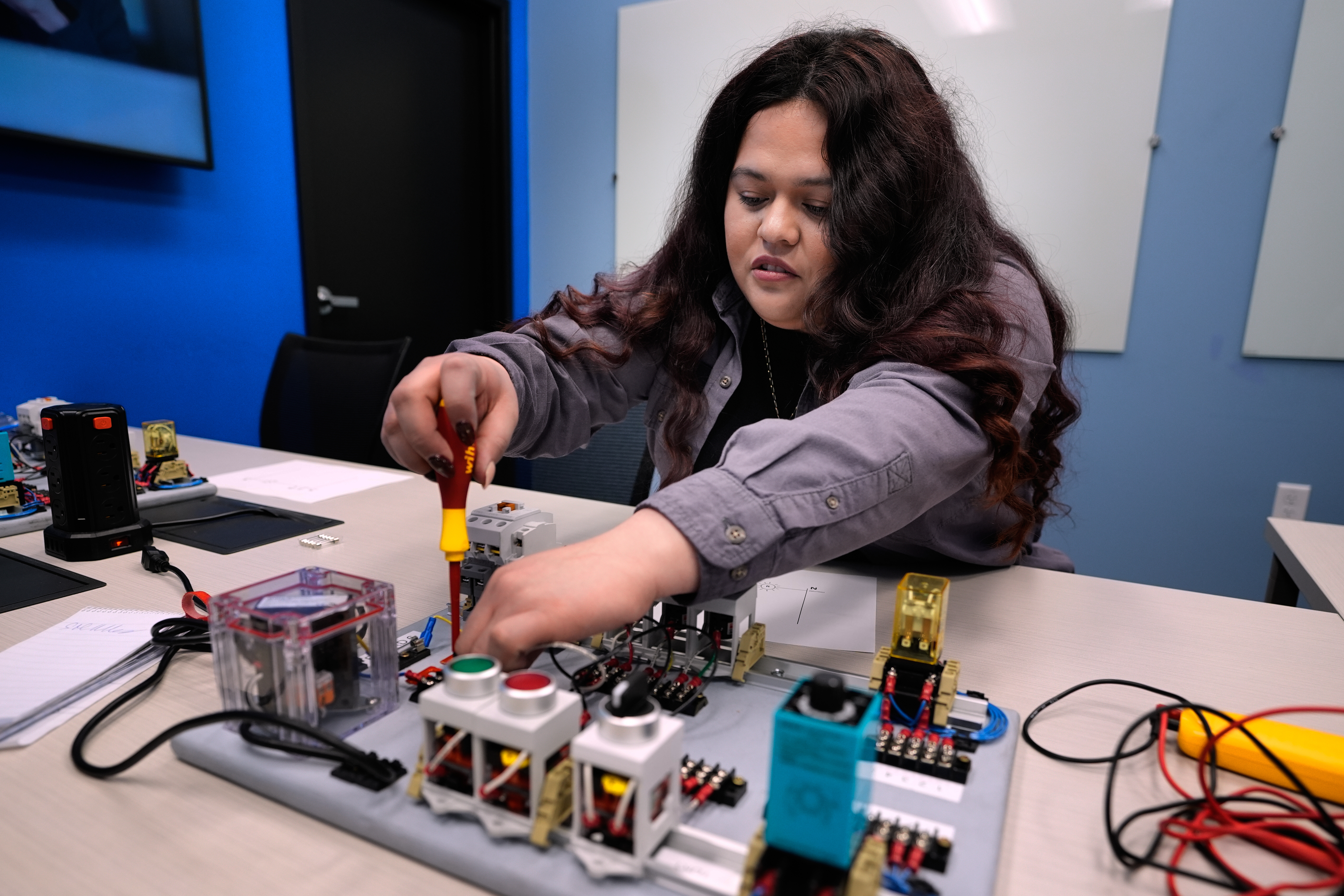 Maintenance technician Liz Cardenas completes a task on an electronics test platform at a training area in a Walmart distribution center Sept. 25, in Bentonville, Ark.