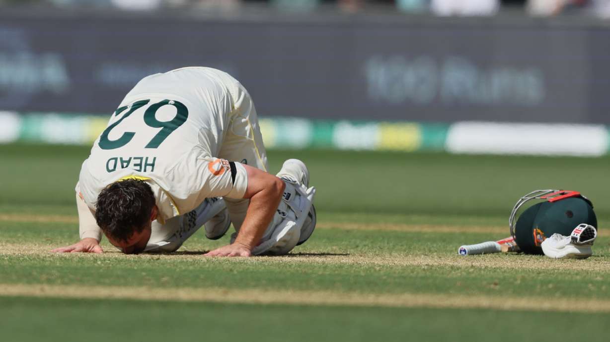 Australia's Travis Head kisses the pitch after scoring a century during play on day three of the third Ashes cricket test between England and Australia in Adelaide, Australia, Friday, Dec. 19, 2025.