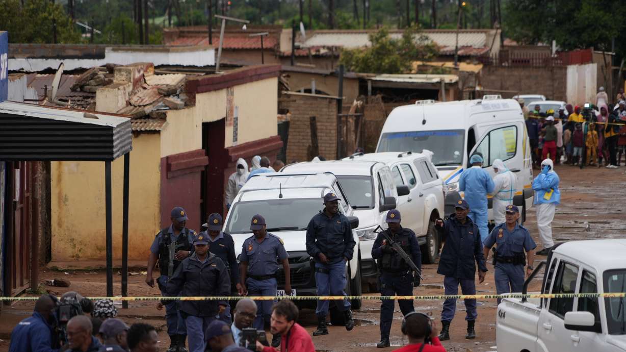 South African police gather at the scene of a mass shooting where gunmen killed nine and injured at least 10 in a pub in Bekkersdal, South Africa, Sunday.