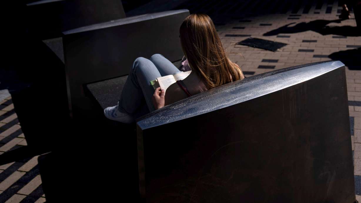 A woman reads a book in the afternoon sun on a bench outside South Station in Boston, on May 31, 2024.