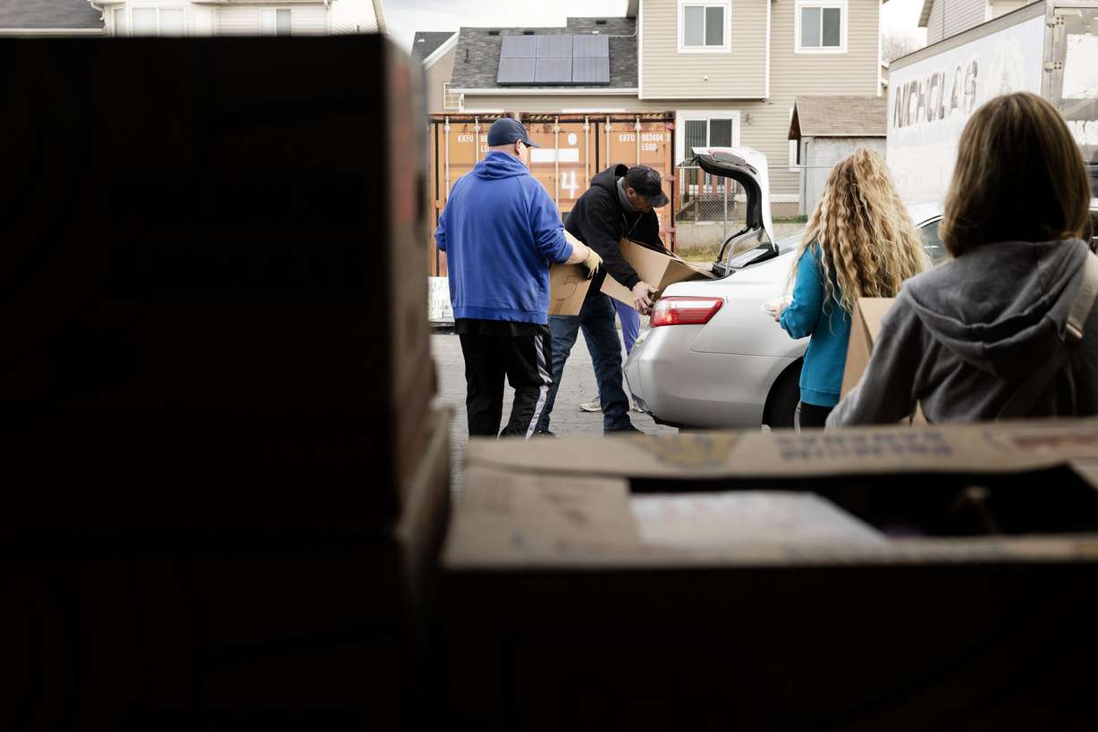Volunteers and Salt Lake City Mission program participants place boxes of food in a car during the mission’s annual “Christmas Food Box Giveaway” in Salt Lake City on Monday.