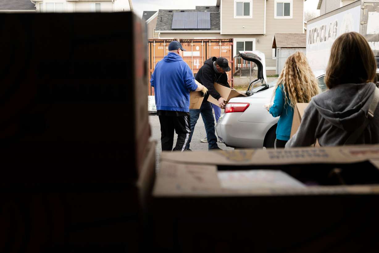 Volunteers and Salt Lake City Mission program participants place boxes of food in a car during the mission’s annual “Christmas Food Box Giveaway” in Salt Lake City on Monday.
