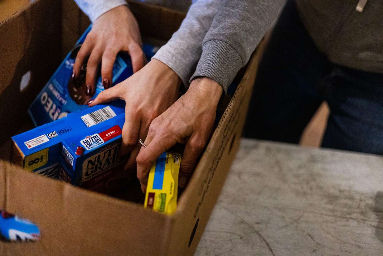 Camille Fisher and her mother Nicole of Salt Lake City fill food boxes during the Salt Lake City Mission’s annual “Christmas Food Box Giveaway” in Salt Lake City on Monday. This is the fourth year the Fishers have volunteered at the event.
