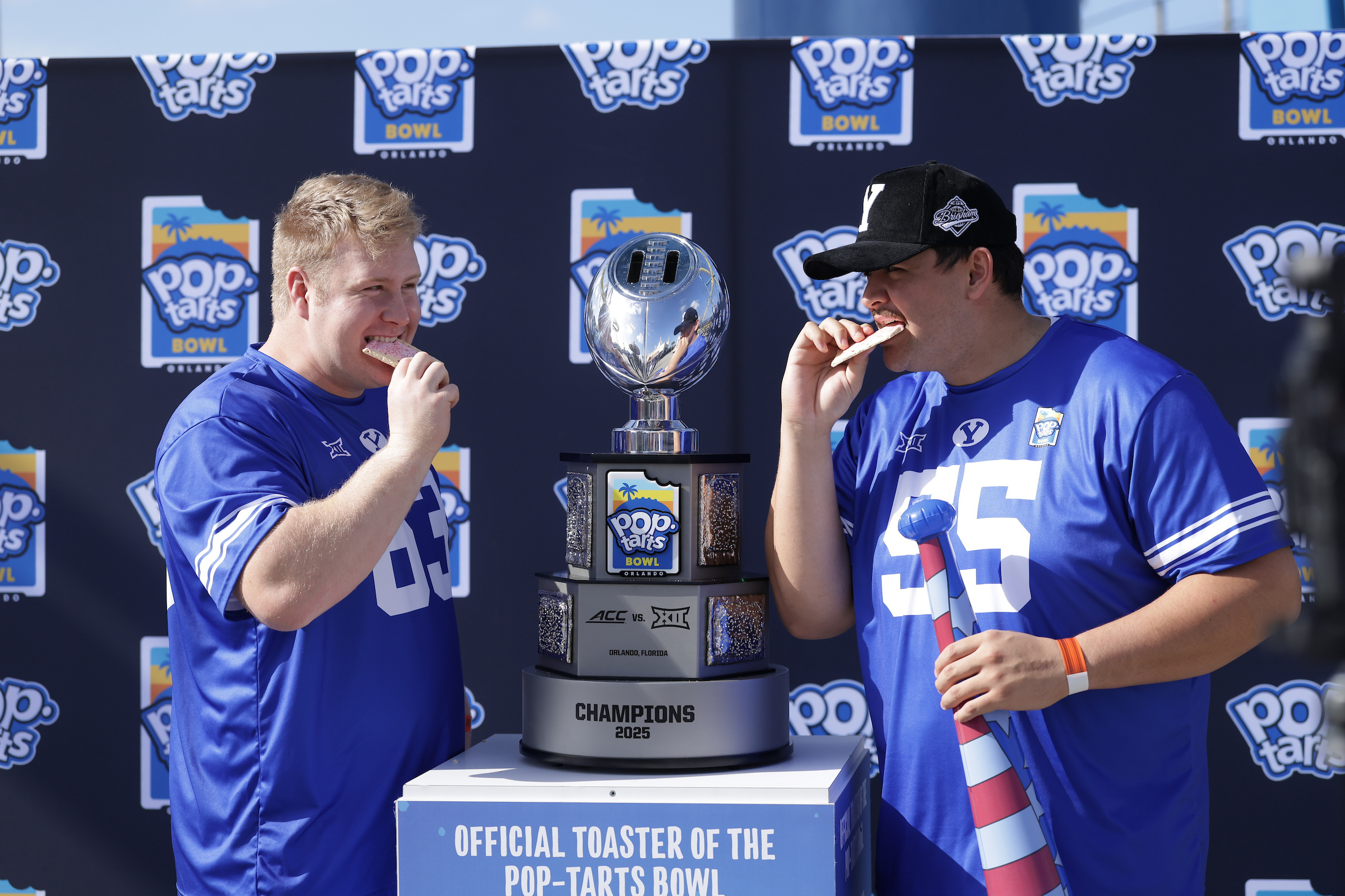 BYU center Bruce Mitchell, left and guard Austin Leausa enjoy a Pop-Tarts from the bowl trophy as part of Kids' Day at Fun Spot America as part of Pop-Tarts Bowl week, Tuesday, Dec. 23, 2025 in Orlando, Florida.