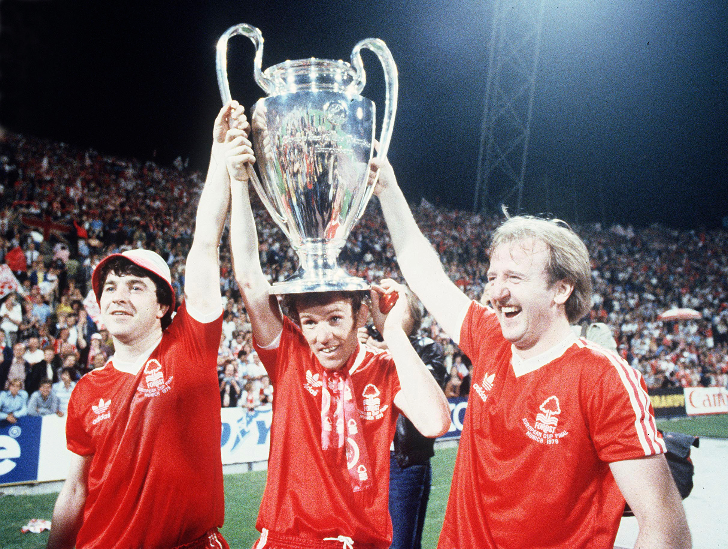 FILE - Nottingham Forest's John Robertson, left, Ian Bowyer, center, and Kenny Burns, right, carry the European Cup in triumph after their 1-0 win against Malmo FF in Munich, Germany, May 30, 1979.