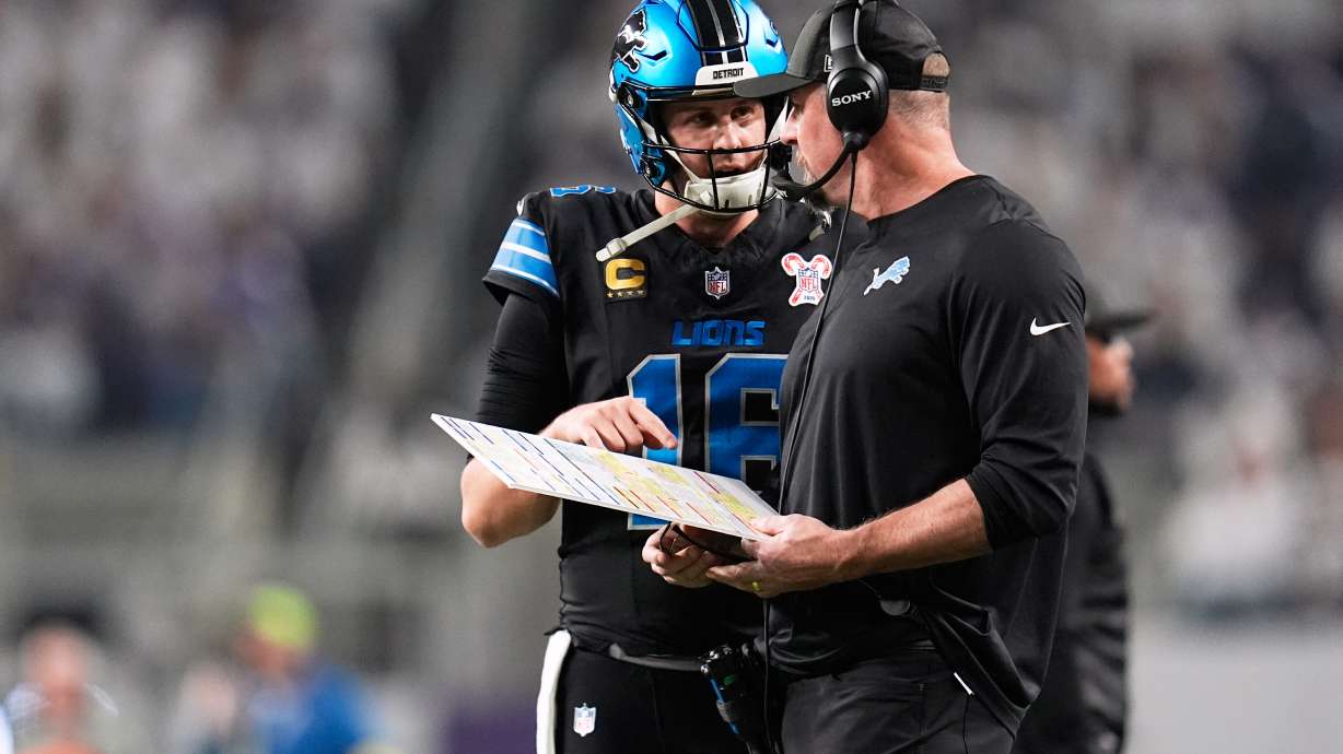 Detroit Lions quarterback Jared Goff, left, speaks with head coach Dan Campbell during the first half of an NFL football game against the Minnesota Vikings, Thursday, Dec. 25, 2025, in Minneapolis.