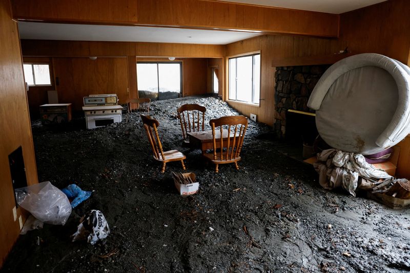 Chairs and a table stand partially buried inside a damaged house as heavy rains from an atmospheric river fall in Wrightwood, California, on Friday.