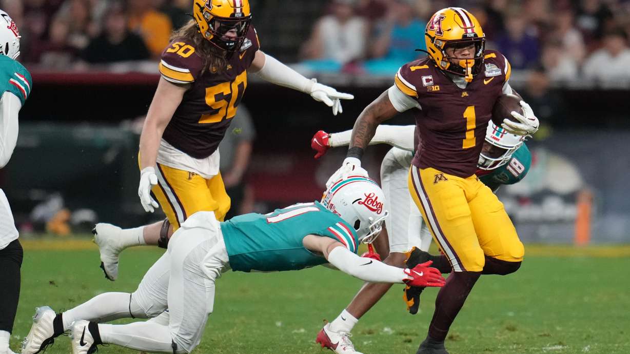 Minnesota running back Darius Taylor (1) runs around New Mexico safety Austin Brawley in the first half of a Rate Bowl NCAA college football game, Friday, Dec. 26, 2025, in Phoenix.