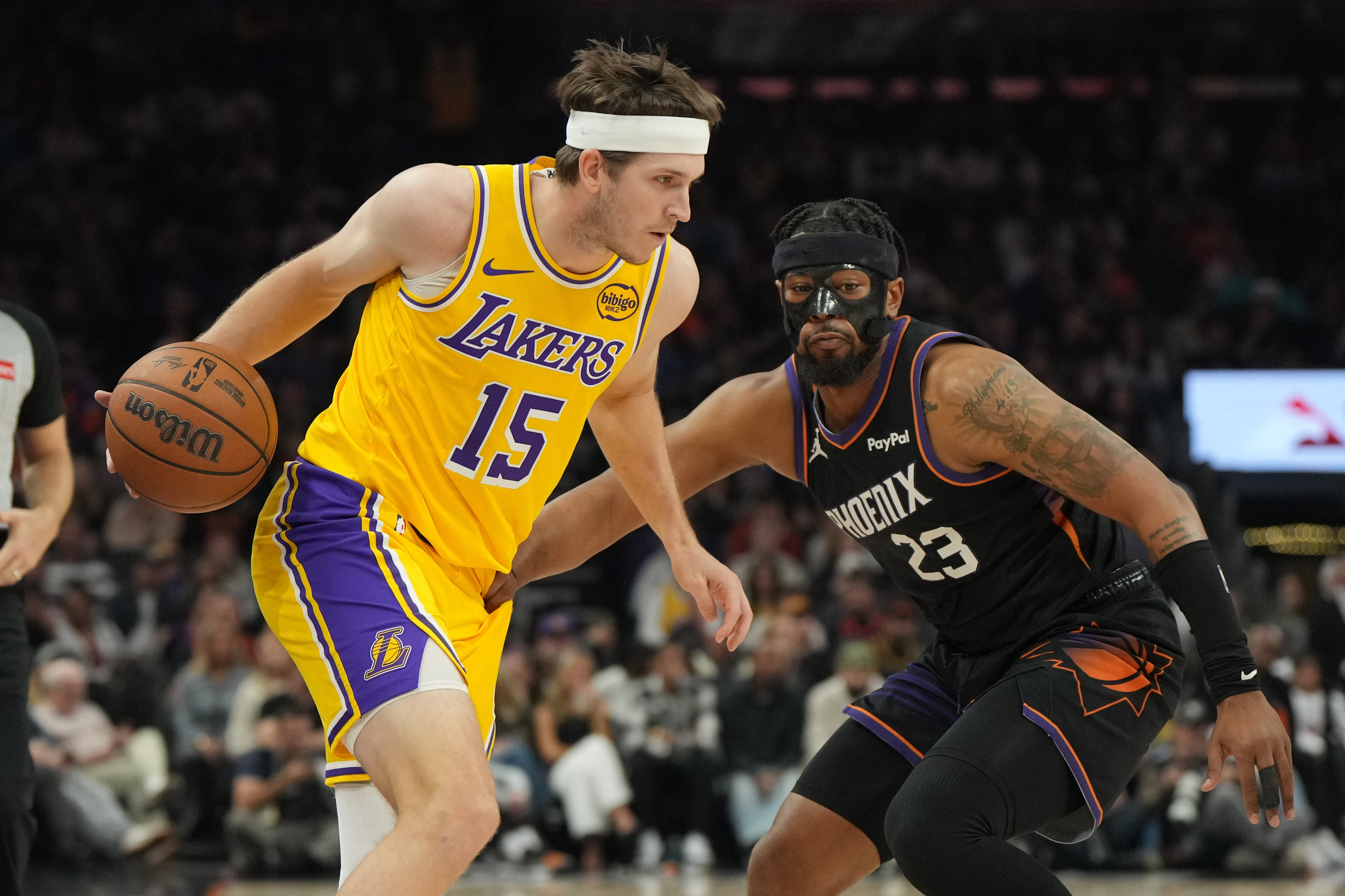 Los Angeles Lakers guard Austin Reaves shields the ball from Phoenix Suns guard Jordan Goodwin (23) during the first half of an NBA basketball game, Tuesday, Dec. 23, 2025, in Phoenix.