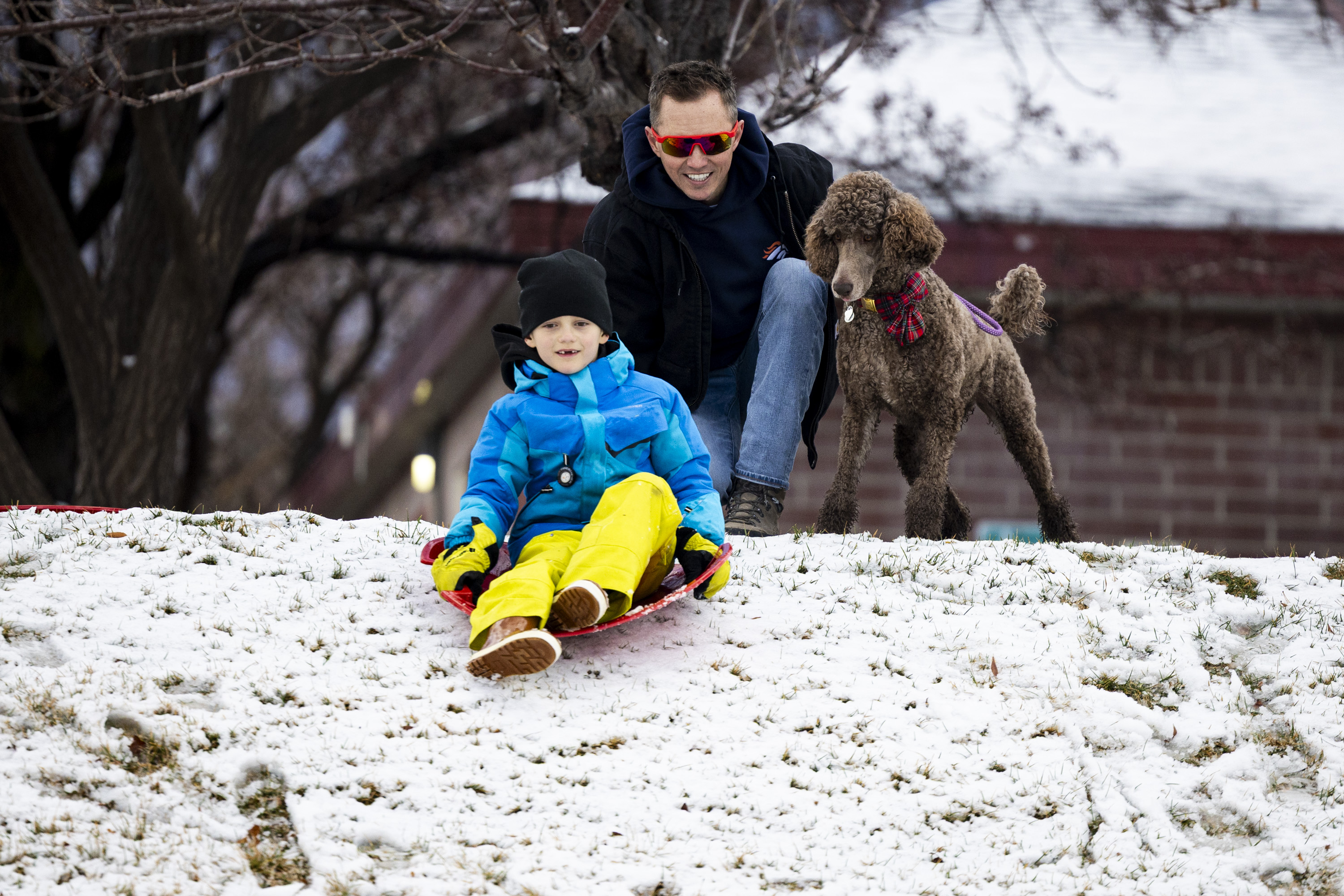 Nick Scano, of Sandy, gives his son Enzo, 6, a push to get going down a hill on a sled while they’re joined by their dog, Birdie, at Storm Mountain Park in Sandy on Saturday.
