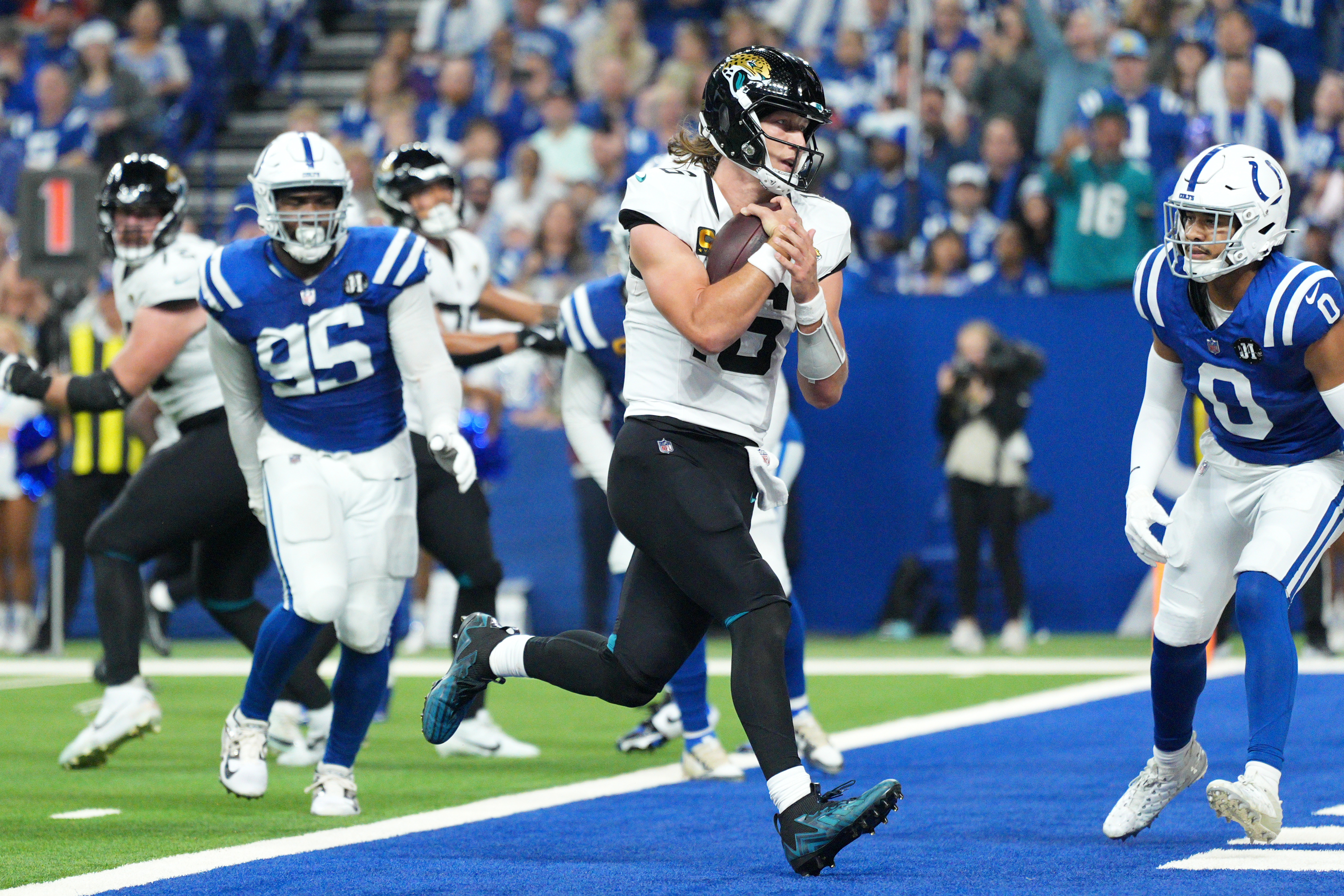 Jacksonville Jaguars quarterback Trevor Lawrence scores past Indianapolis Colts defensive tackle Adetomiwa Adebawore (95) and safety Camryn Bynum (0) during the second half of an NFL football game Sunday, Dec. 28, 2025, in Indianapolis.