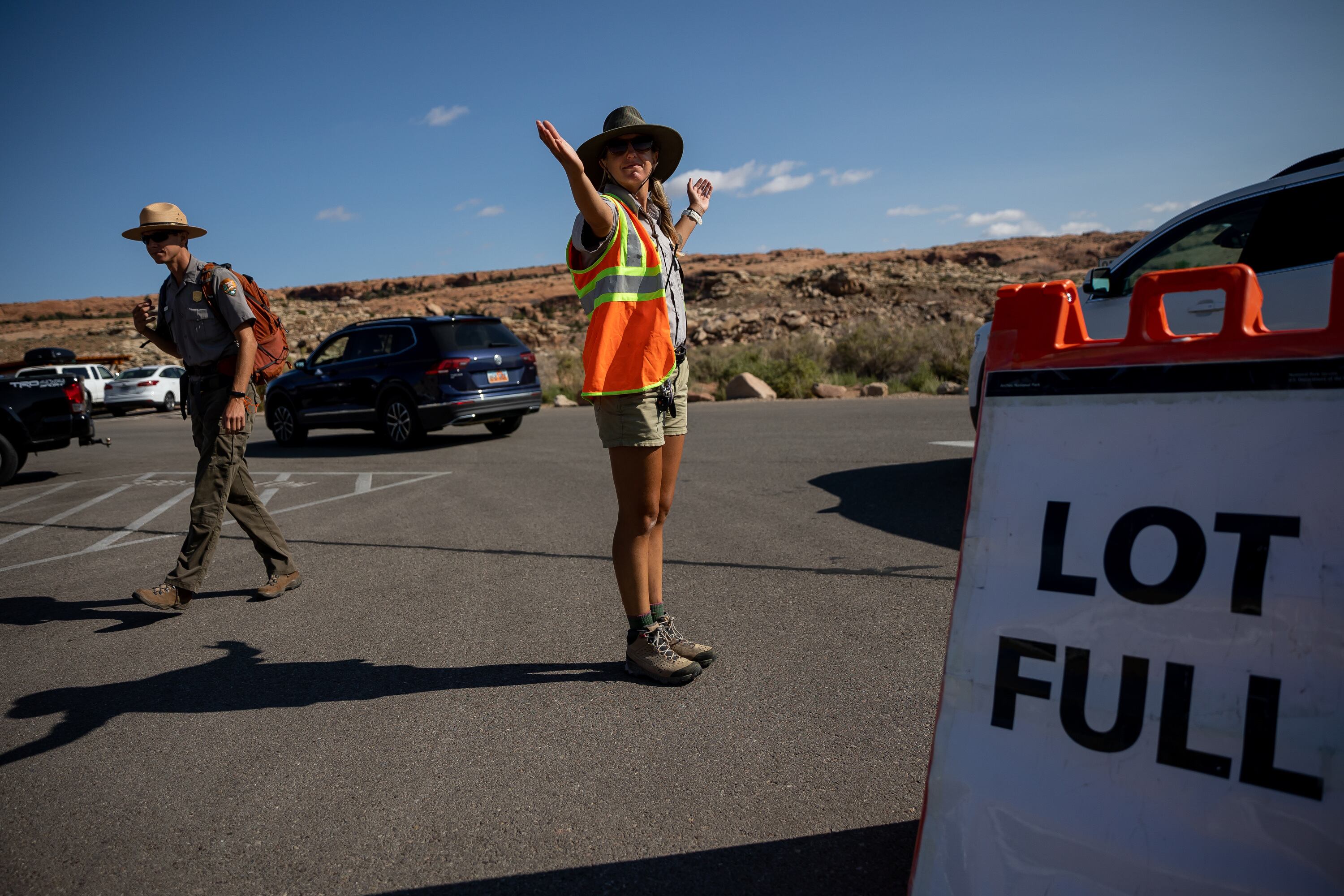 A visitor services assistant directs traffic around the full Wolfe Ranch parking lot, which serves as the starting point for the popular hike to Delicate Arch in Arches National Park on Sept. 19, 2021. National parks were hit hard when staffing was slashed by the Department of Government Efficiency on Feb. 14.