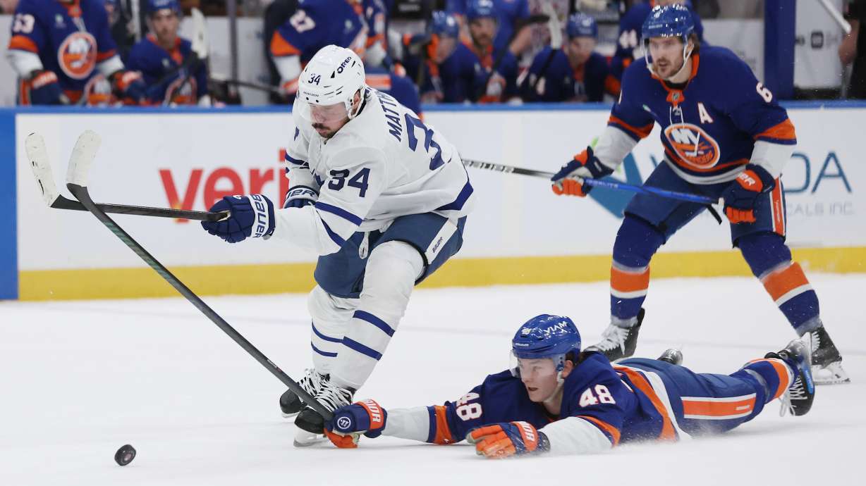 New York Islanders' Matthew Schaefer (48) reaches for the puck against Toronto Maple Leafs center Auston Matthews (34) during the first period of an NHL hockey game, Saturday, Jan. 3, 2026, in New York.