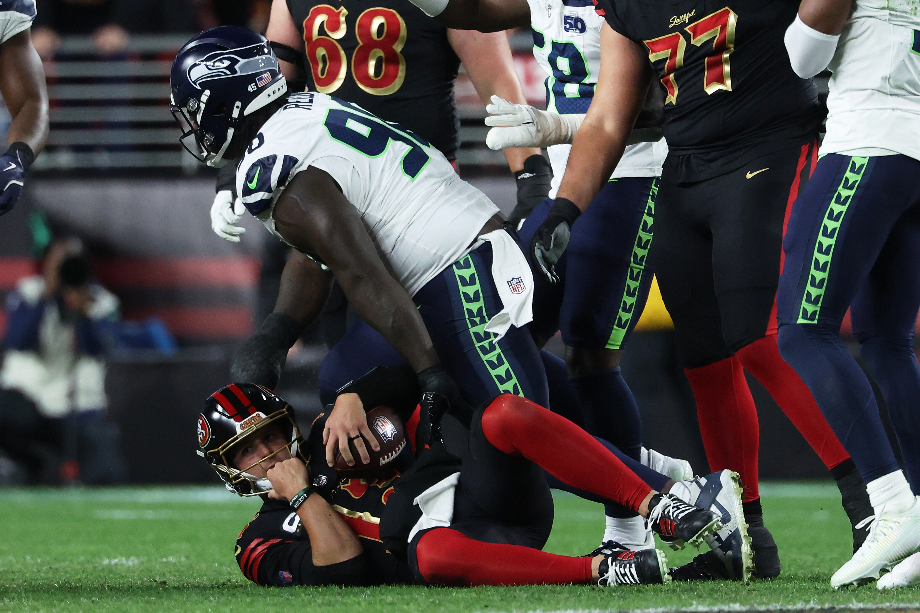 San Francisco 49ers quarterback Brock Purdy, bottom, reacts after being sacked by Seattle Seahawks defensive tackle Jarran Reed, middle, during the second half of an NFL football game in Santa Clara, Calif., Saturday, Jan. 3, 2026.