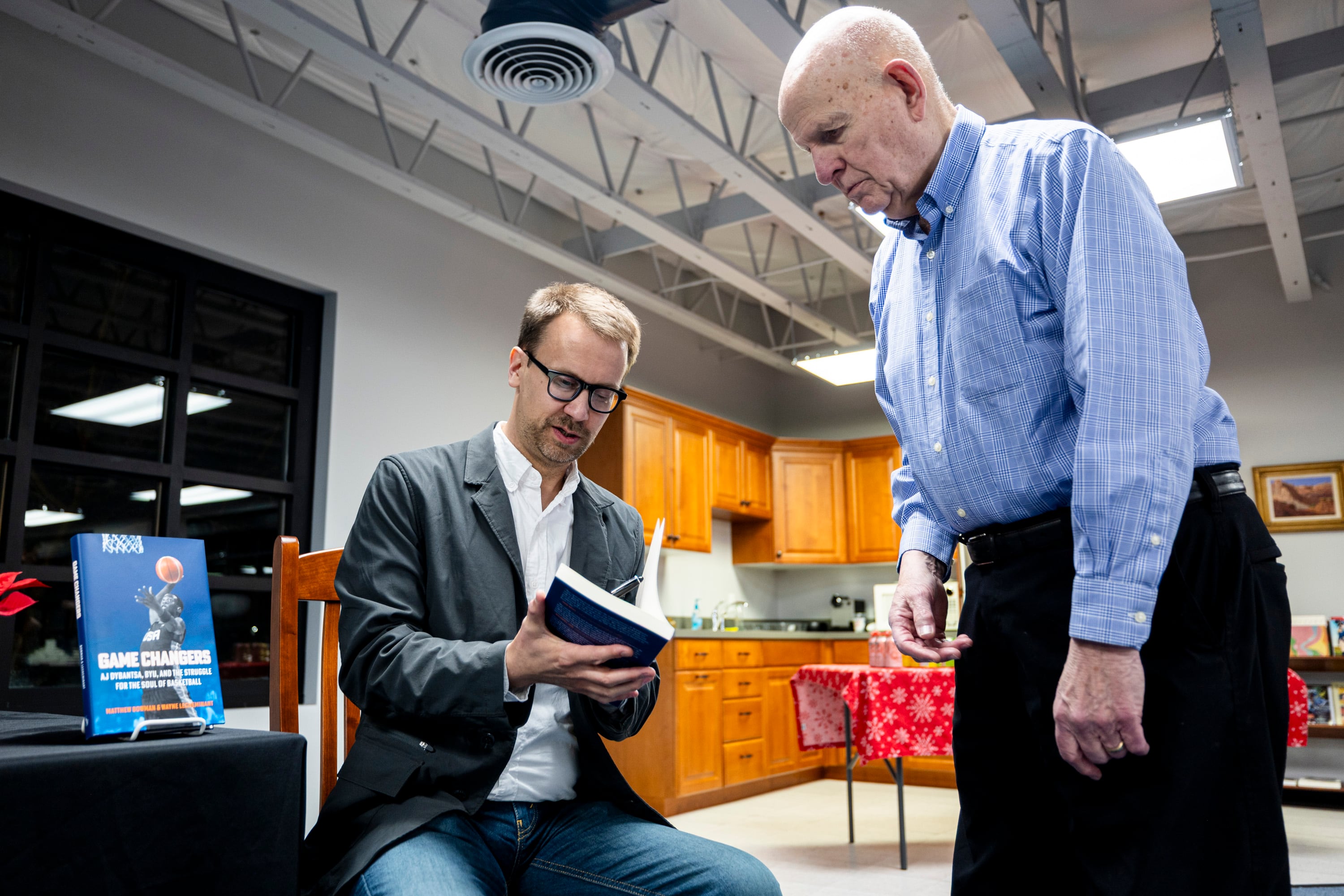 Matthew Bowman, who co-authored the book “Game Changers” with Wayne LeCheminant, signs a copy of the book for Dale Rees, of Sandy, before an event held at Signature Books in Salt Lake City on Dec. 18, 2025.