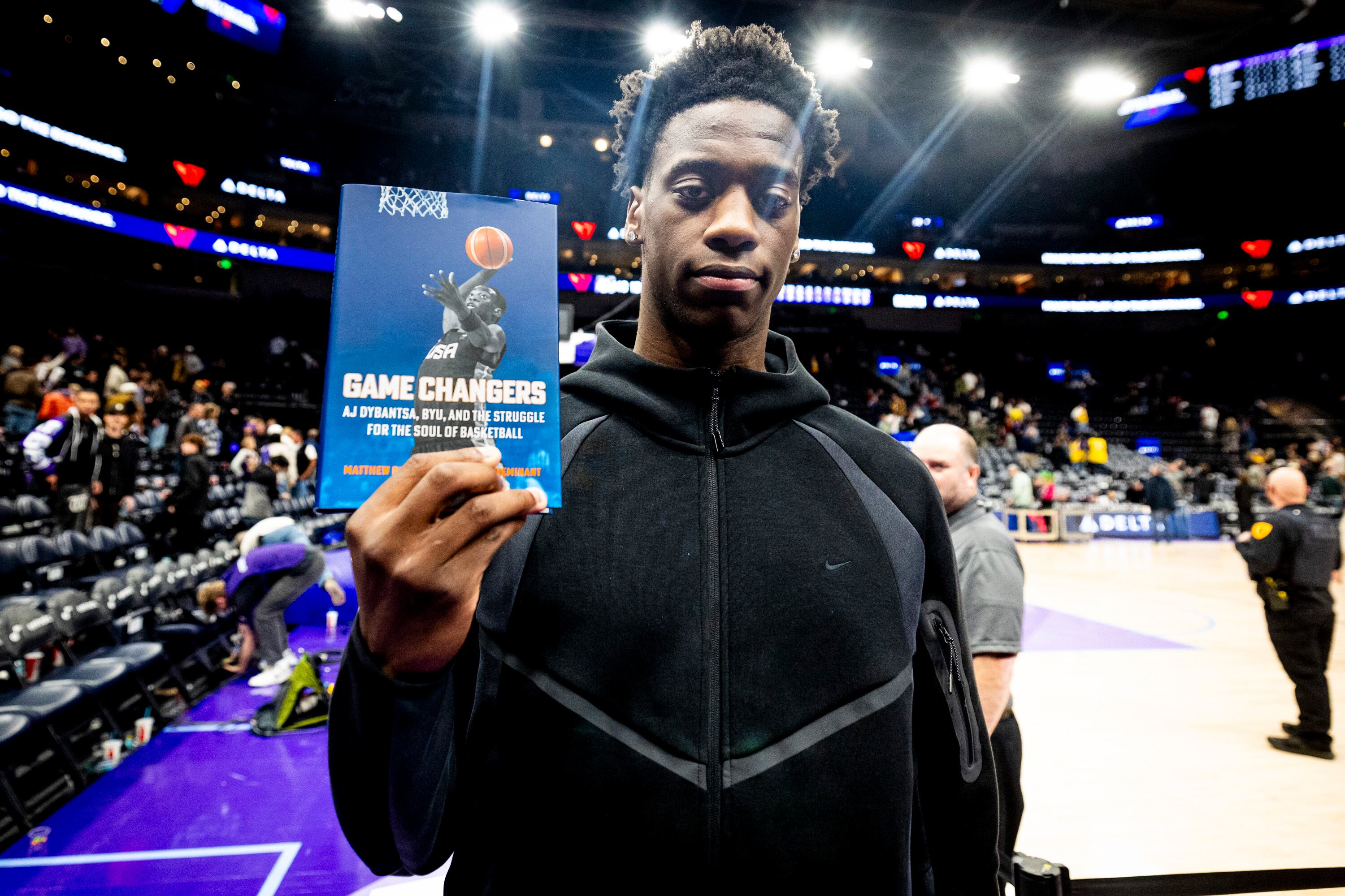 BYU forward AJ Dybansta poses with a copy of the book “Game Changers” after an NBA game between the Utah Jazz and the Los Angeles Lakers at the Delta Center in Salt Lake City on Dec. 18, 2025.