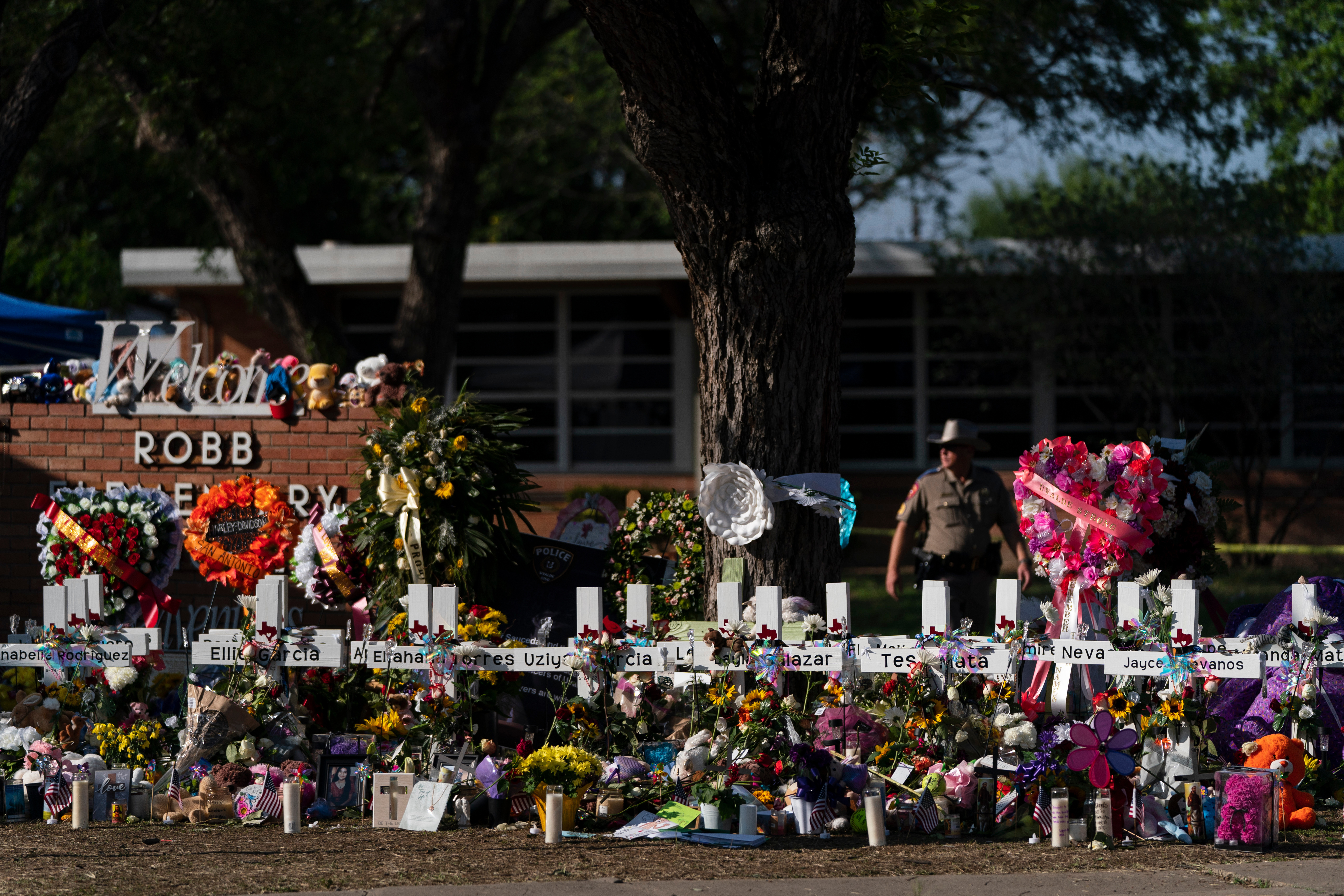 Flowers and candles are placed around crosses to honor the victims killed in a school shooting, May 28, 2022, outside Robb Elementary School in Uvalde, Texas.