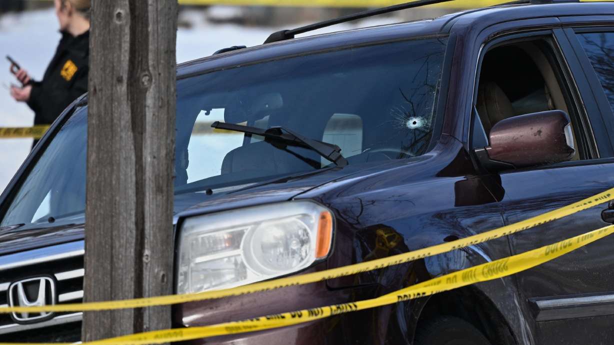 A bullet hole is seen in the windshield as law enforcement officers work at the scene of a shooting involving federal law enforcement agents, Wednesday, in Minneapolis. A federal officer shot and killed a Minneapolis motorist when she allegedly tried to run over law enforcement officers during an immigration crackdown in the city, authorities said Wednesday.