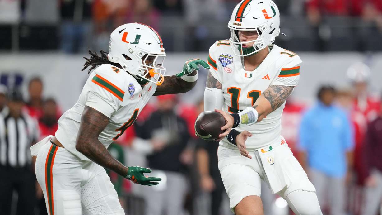 Miami quarterback Carson Beck, right, prepares to hand off to running back Mark Fletcher Jr. during the first half of the Cotton Bowl College Football Playoff quarterfinal game against Ohio State Wednesday, Dec. 31, 2025, in Arlington, Texas.