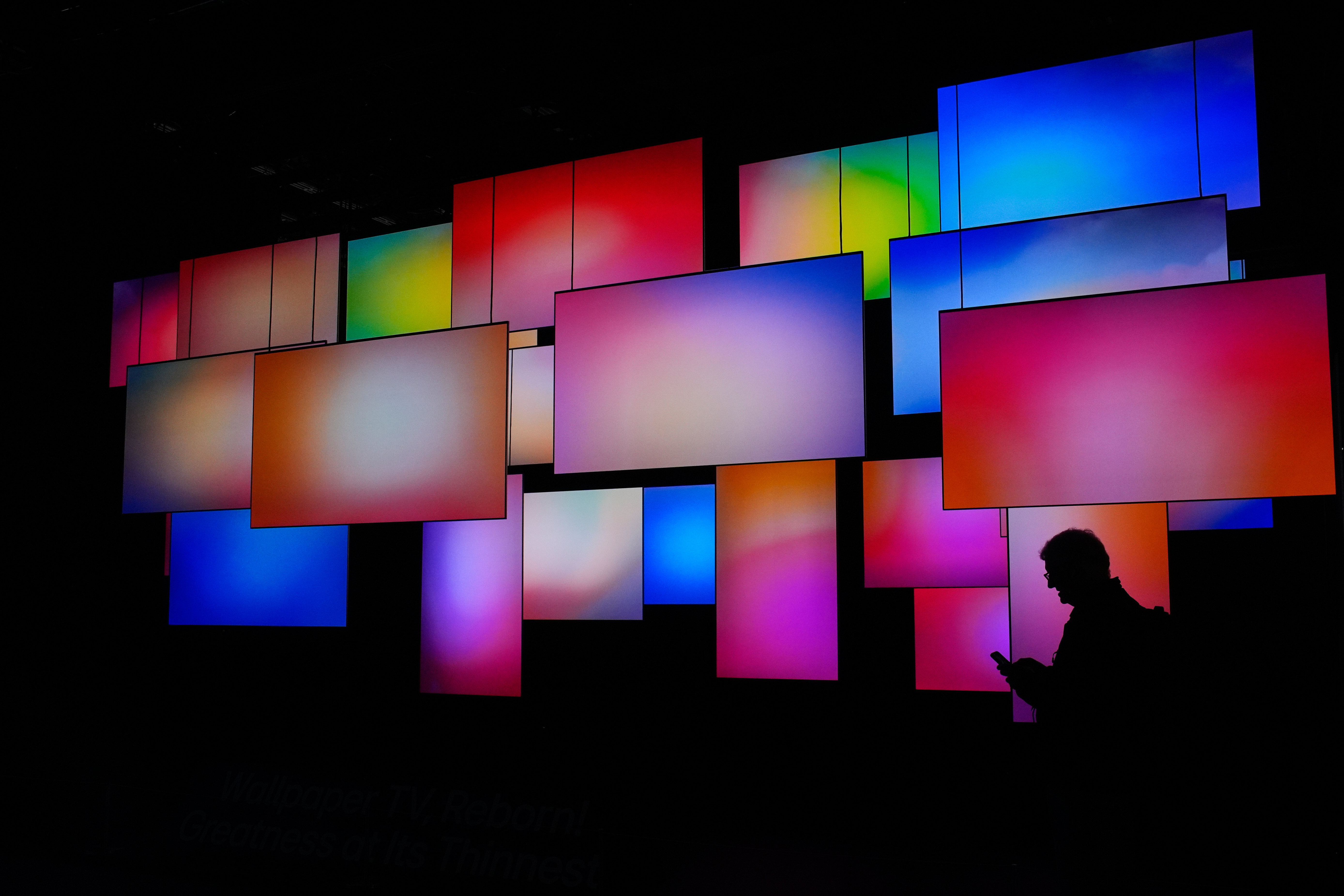 A Person walks past a wallpaper TV display at the LG booth during the CES tech show Wednesday, in Las Vegas. Samsung and LG both revealed competing innovations at the show.