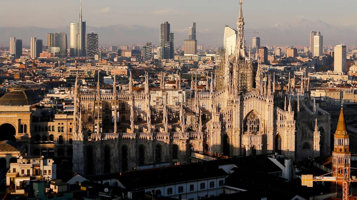 FILE - The pinnacles of the Duomo cathedral are lit by the afternoon declining sun and backdropped by the new Business Center in Milan, northern Italy, Jan. 4, 2017.