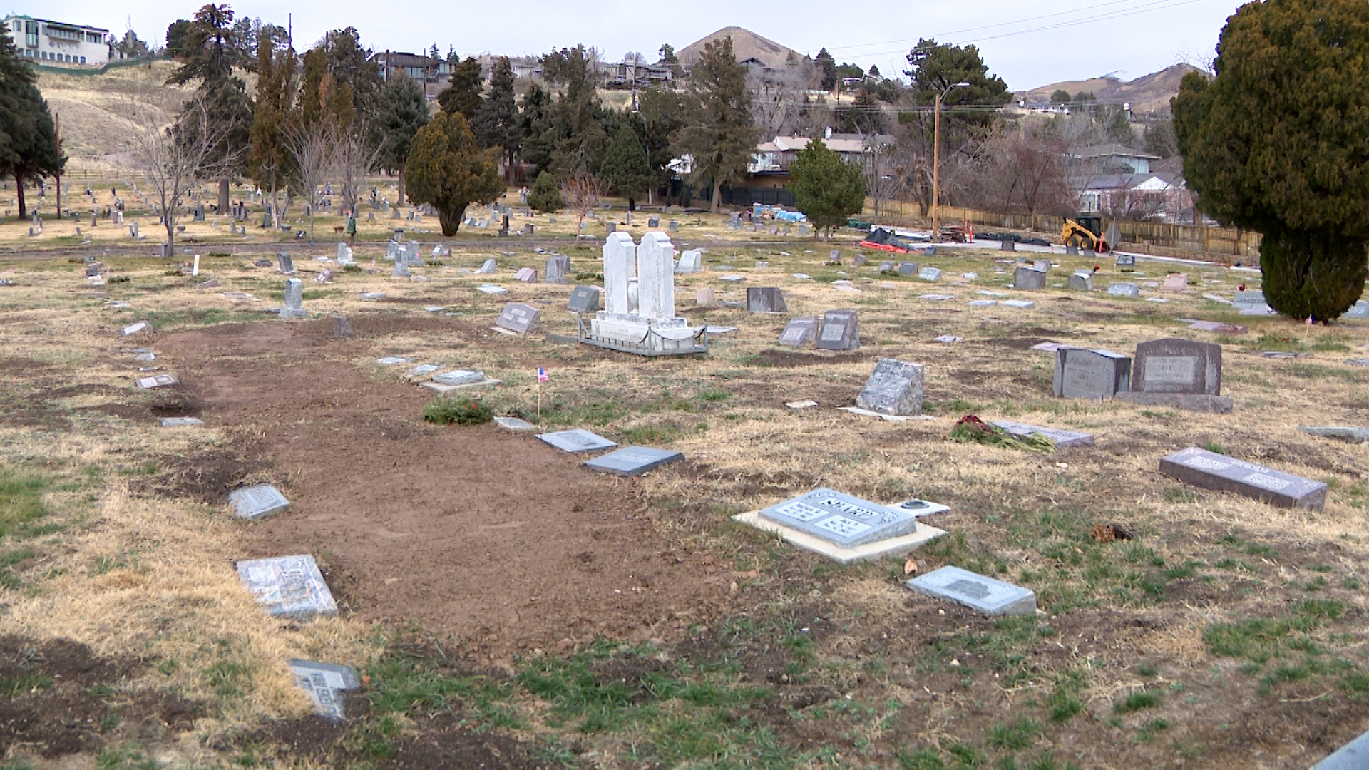 Several headstones at the Salt Lake Cemetery are shown visibly sunken, tilted or covered by displaced soil.